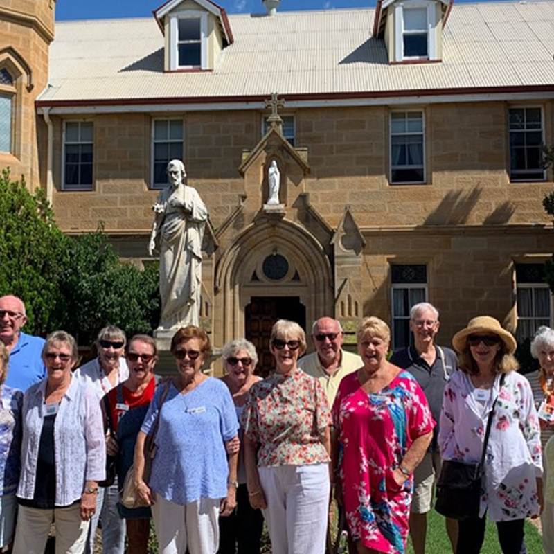 A group of people standing in front of a church during one of the best escorted tours for seniors in Queensland.