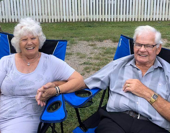 An elderly couple relaxing in lawn chairs.