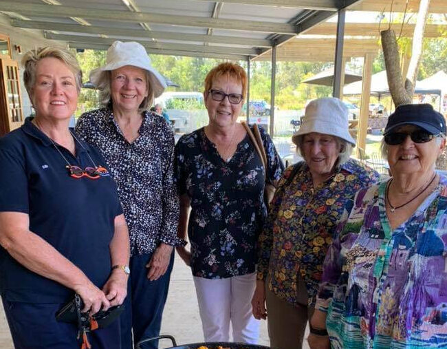 A group of women posing for a photo at a grill during one of the best escorted tours for seniors in Queensland.