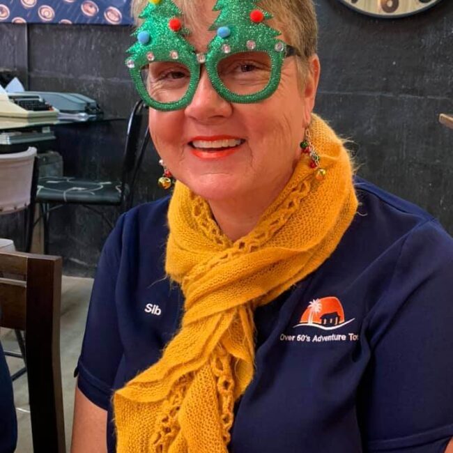 Two women wearing Christmas glasses at a table during the best escorted tours for seniors in Australia.
