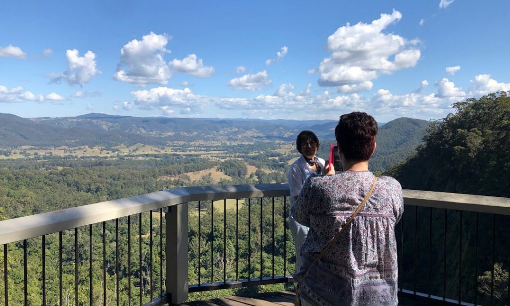 Two people standing at the top of a mountain admiring the valley below during an Australia local tour package.