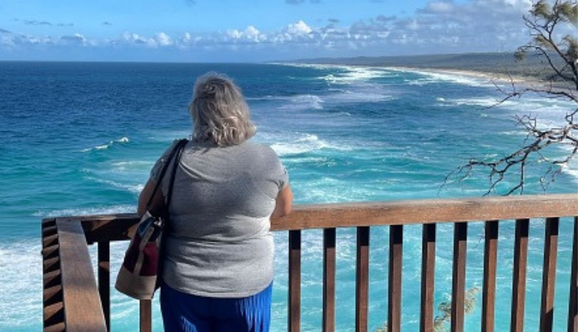 Person standing at a lookout, observing the vast ocean and coastline during the Tamworth Country Music Festival.